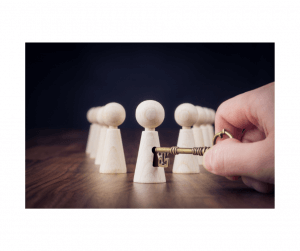 A hand holding a golden key in front of wooden figurines on a table, symbolizing access.